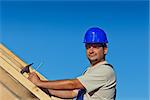 Proud construction worker on the roof structure with nail and hammer