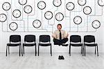 Expert time management - businessman controlling lots of wall clocks