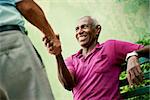 retired elderly people and free time, happy senior african american and caucasian male friends greeting and sitting on bench in park