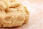 Detail of a fresh ball of pastry on a floured wooden board