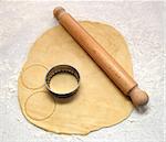Rolling pin and cutter on fresh pastry, cutting out circles on a floured surface