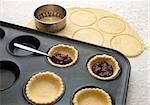 Cutting and filling pastry shapes to make jam tarts
