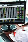 view of desk with computer monitor, stock info, papers, grocery list and notebook