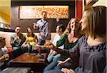 Men and women socializing in a bar in the city. Group of festive, smiling people celebrating with drinks. California USA