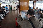 Back view of a man reading a Chinese newspaper onboard a Star Ferry, Hong Kong, China, Asia