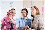 Business People Working in Office Looking at Plans Displayed on a Glass Board