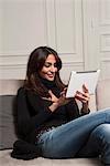 Woman using tablet computer on sofa