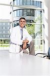 Doctor sitting on desk in meeting room