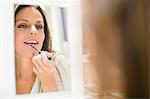 Woman trying on lip gloss in store