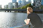 Man overlooking urban river on bridge