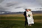 Newlywed couple kissing in rural field