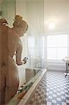 Nude woman using cell phone in shower