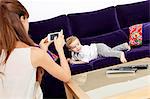 Mother taking picture of son on sofa