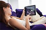 Woman using tablet computer on sofa