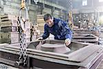 Worker inspecting mould in foundry