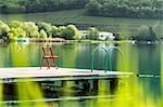 Chair on wooden pier in still rural lake