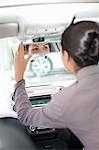 Woman adjusting rearview mirror in car