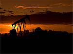 Silhouette of oil well at sunset