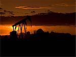 Silhouette of oil well at sunset