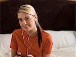 Woman listening to earphones on bed