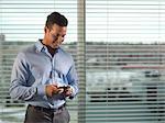 Businessman using cell phone by window