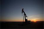 Silhouette of oil well in dry landscape