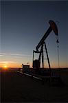 Silhouette of oil well in dry landscape