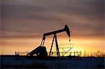 Silhouette of oil well at sunset