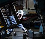 Worker using machinery in metal plant