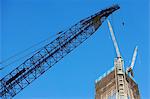 Low angle view of crane and skyscraper