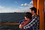 Couple hugging on ferry in urban harbor