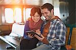 Couple using tablet computer on ferry