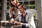 Couple using tablet computer at table