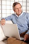 Older man using laptop on sofa