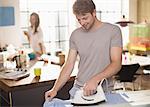 Man ironing shirt in kitchen