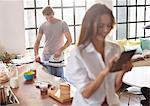 Woman using digital tablet as boyfriend irons in kitchen