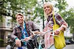 Couple standing on bicycles on city street