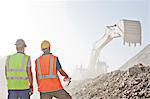 Workers watching digger in quarry