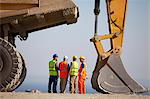 Workers talking by machinery in quarry