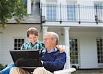Man using laptop with granddaughter outdoors