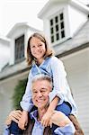 Man carrying granddaughter on shoulder outdoors