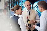 Waiters discussing bottle of wine in restaurant