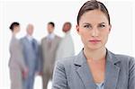 Serious businesswoman with colleagues behind her against a white background