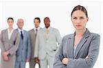 Serious tradeswoman with arms folded and colleagues behind her against a white background