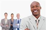 Smiling salesman with team behind him against a white background