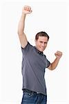 Victorious young man raising fist against a white background