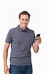 Smiling young man holding his cellphone against a white background