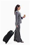 Profile of a businesswoman with a suitcase and holding a coffee against white background
