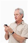 Mature man typing text message on his cellphone against a white background
