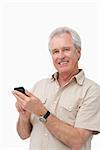 Smiling mature male typing a text message against a white background